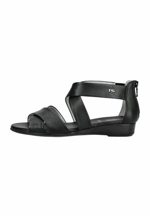 Černá kožená sandála na plochém podrážce s překříženými pásky, zipem u kotníku a malým stříbrným logem na bočním pásku.