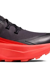 Schwarzer und roter Sportschuh mit dicker roter Sohle, schwarzem Stoffobermaterial und Schlaufenösen auf weißem Hintergrund.