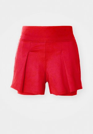 Shorts rouges avec une taille élastique, présentant des plis à l'avant et une texture lisse. Longueur courte avec une coupe décontractée.