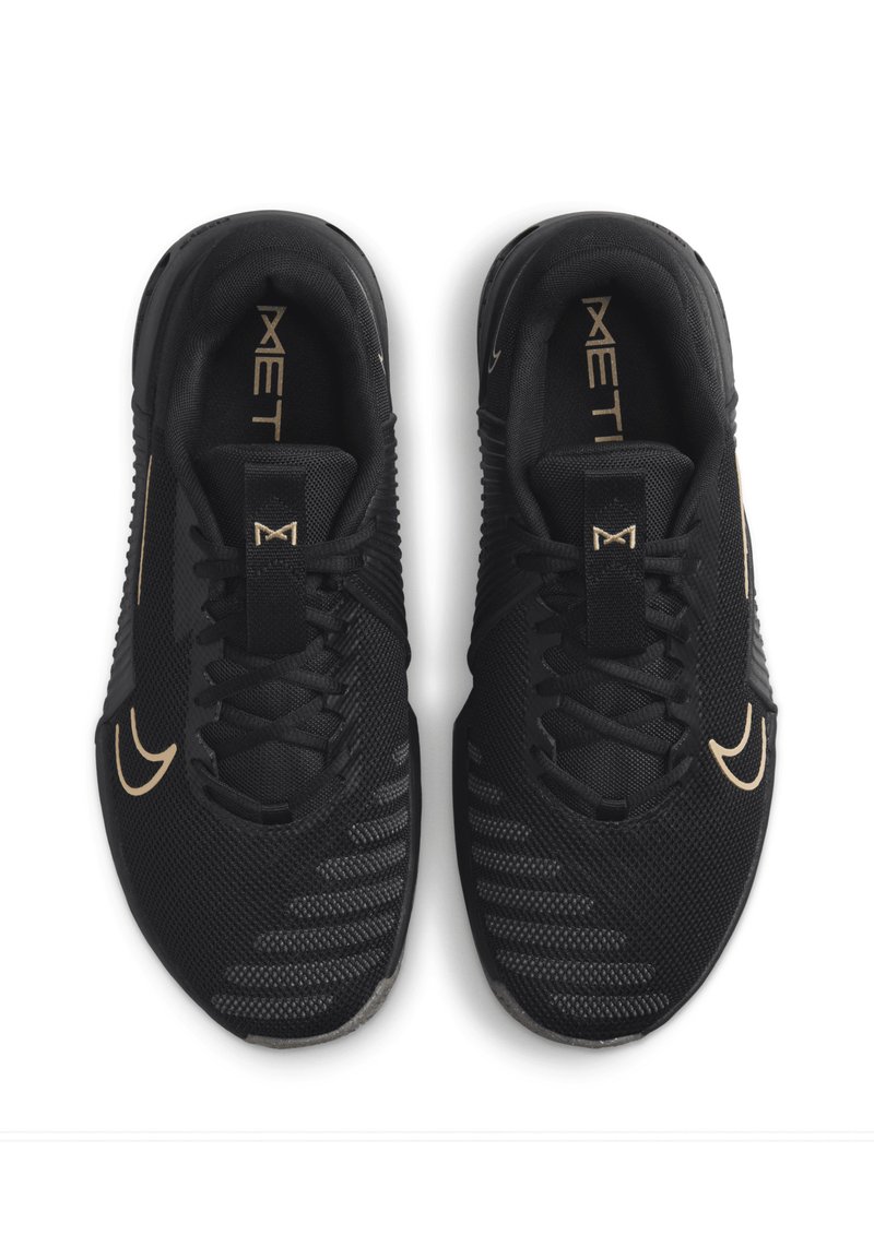 Zwarte sportieve schoenen van mesh materiaal, met een gestructureerde bovenzijde, platte veters en gouden accenten op het logo en de details.