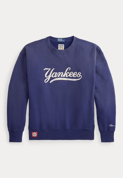 Sudadera azul marino de tela suave con el logo en forma de palabra "Yankees" en blanco en el frente, puños y cintura acanalados, y una etiqueta roja de Polo.