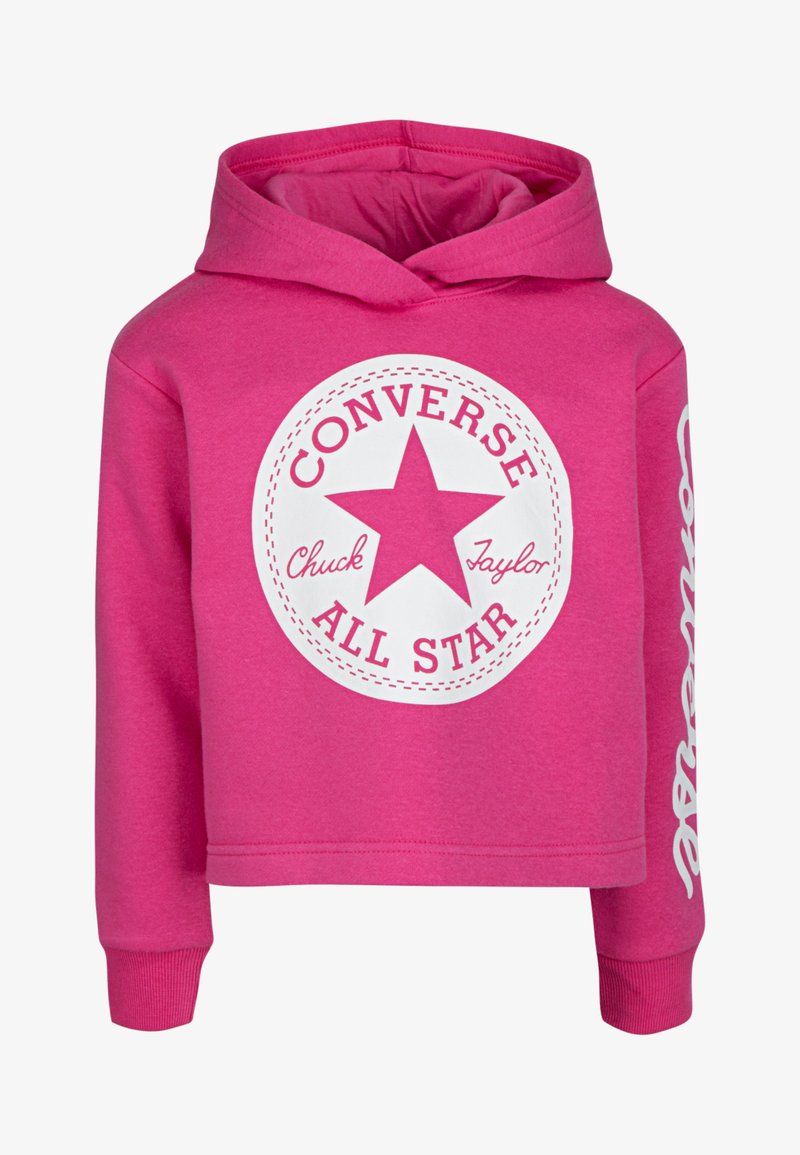 Ροζ cropped hoodie σε μαλακό ύφασμα, με λευκό κυκλικό λογότυπο που περιλαμβάνει ένα αστέρι και κείμενο, καθώς και λευκή γραφική παράσταση στο μανίκι.