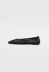 Ballerine en crochet noire avec un bout pointu, présentant un design en mailles ouvertes et une semelle plate.