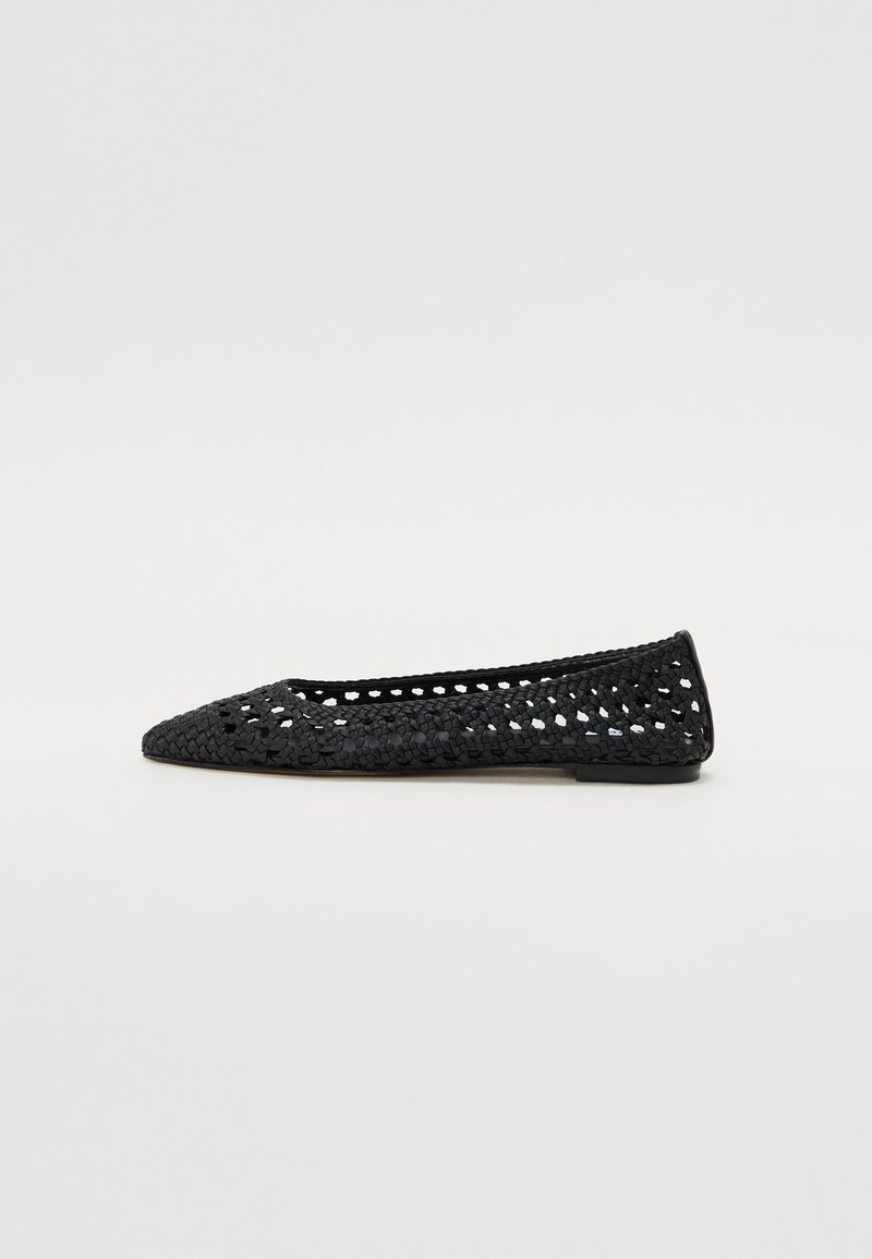Ballerine en crochet noire avec un bout pointu, présentant un design en mailles ouvertes et une semelle plate.