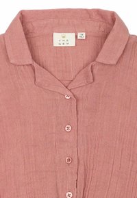 Camisa de lino rosa claro con cuello, que cuenta con cinco botones y una tela texturizada. La etiqueta indica la talla y el origen.