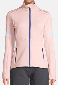 Giacca rosa chiara con zip, realizzata in morbido tessuto, caratterizzata da un colletto alto, zip blu, dettagli bianchi sulle maniche e tasche laterali.
