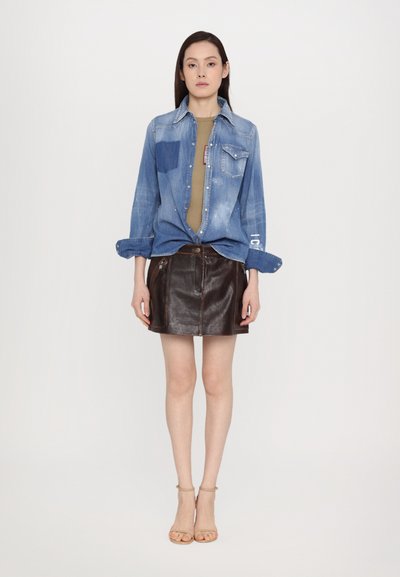 Denim shirt in light blue with long sleeves, paired with a brown leather mini skirt. Tan strappy sandals complete the outfit.