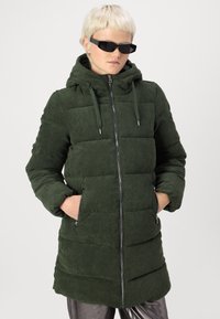 Abrigo acolchado de pana verde con capucha, que presenta un cierre frontal, cordones elásticos y bolsillos laterales, en un diseño texturizado y acanalado.