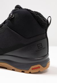 Bota de senderismo negra con un upper texturizado, un cuello acolchado y suela Contagrip con un patrón de agarre para una tracción mejorada.