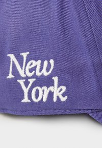 Purple cap featuring white embroidered text reading "New York." The fabric has a textured finish with visible stitching details.