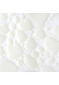 Liquid blanc avec des gouttes et des bulles de tailles variées et irrégulières sur un fond blanc, créant une apparence texturée et mousseuse.