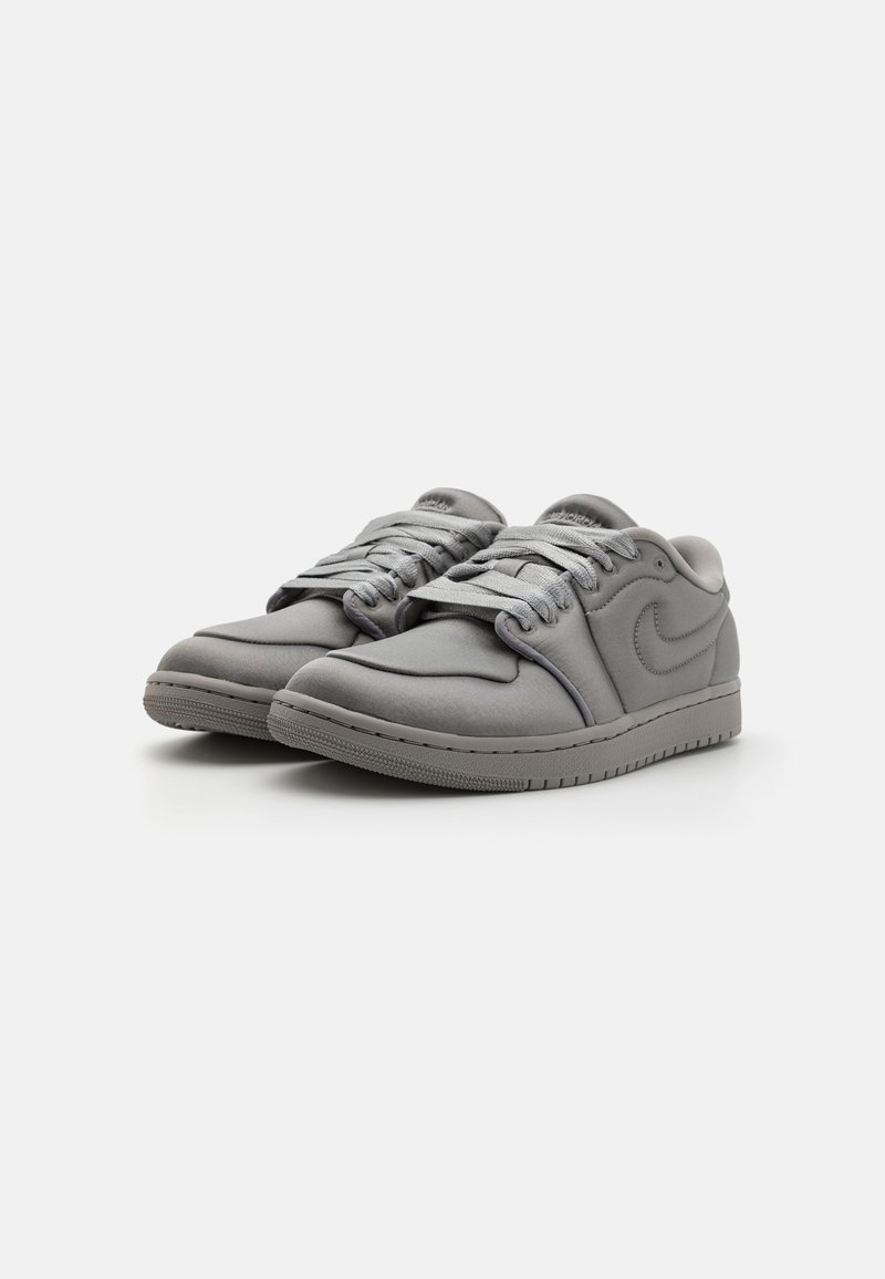 Zapatillas grises con un acabado suave y mate, que cuentan con una puntera redondeada, un diseño clásico de cordones y una suela de goma texturizada. Logo destacado en el costado.