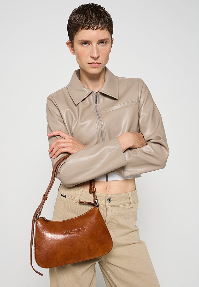 Braune Lederhandtasche mit geschwungener Form und kurzem Tragegurt. Die Tasche besitzt eine glatte Textur und dezente geprägte Logodetails.