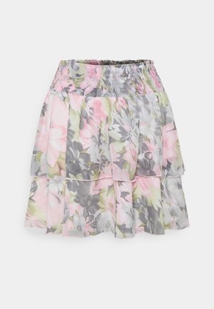 Jupe tiered florale avec une taille smockée, fabriquée en tissu léger dans des teintes rose, gris, vert et blanc, avec des textures douces.