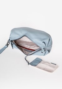 Borsa a mano in pelle azzurro chiaro con superficie texturizzata, chiusura con zip e interni con motivo geometrico. Include un pochette abbinata.