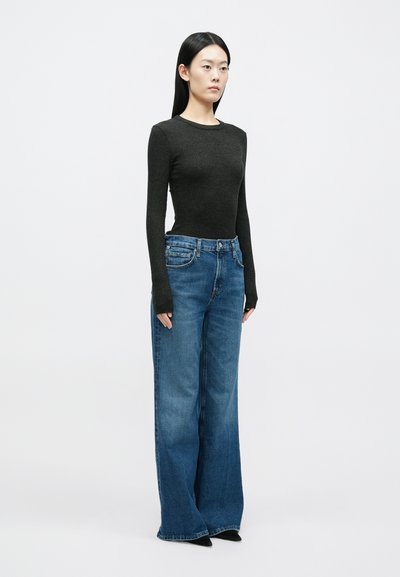 Μπλούζα μακρυμάνικη σε σκουρό γκρι χρώμα σε συνδυασμό με τζιν μπλε με φαρδιά μπατζάκια. Η μπλούζα έχει ριμπ υφή, ενώ το τζιν διαθέτει κλασικό σχεδιασμό με πέντε τσέπες.