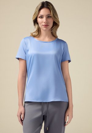 Top azzurro chiaro a maniche corte realizzato in tessuto morbido, con scollatura rotonda e una vestibilità comoda. Nessun motivo o dettaglio notevole presente.