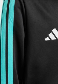 Felpa nera con strisce turchesi lungo le maniche e un logo bianco con tre strisce diagonali sul petto.