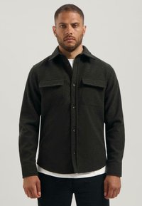 Donkergroene flanellen shirt met een kraag, knoopsluiting aan de voorkant, twee borstzakken en lange mouwen. Het shirt heeft een gestructureerde stof en een rechte zoom.