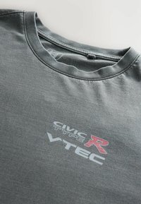 Szürke pamut póló, kerek nyakkivágással, elöl piros "CIVIC TYPE R" és fehér "VTEC" felirattal. Sima textúra, laza illeszkedés.