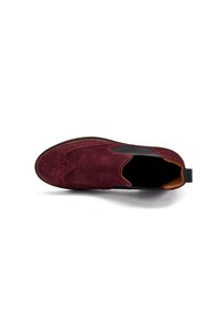 Scarpe slip-on in suede bordeaux con design brogue, caratterizzate da un bordo curvo, lati elasticizzati e una fodera in contrasto color tan con tacco nero.