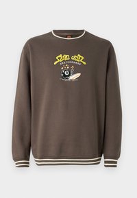 Felpa marrone con dettagli crema, colletto tondo e polsini a coste. Presenta una grafica ricamata colorata di una palla da bowling e una tavola da surf.