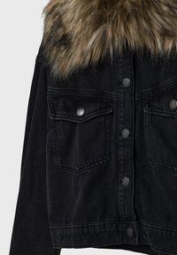Black denim jacket featuring a faux fur collar, snap button closures, and two front pockets. The fabric has a textured finish.