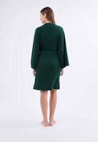 Zelený župan ke kolenům s dlouhými rukávy a páskem. Vyroben ze měkkého materiálu s postranními rozparky pro snadný pohyb.