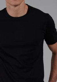 Black crew-neck t-shirt, short sleeves, smooth cotton fabric, fitted shape, minimal seams, and no visible graphics or patterns.