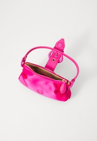 Ροζ δερμάτινη τσάντα με στρογγυλό λογότυπο, λεία υφή, χρυσό φερμουάρ, αποσπώμενο λουρί και σατέν γυαλάδα; ανοικτή που δείχνει ένα μπεζ εσωτερικό.