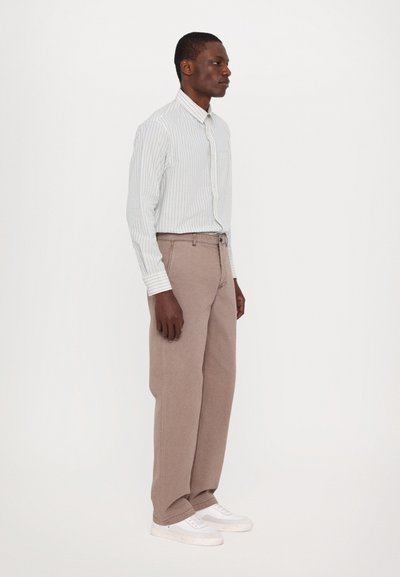 Striped long-sleeve button-up shirt in light blue and white, paired with beige wide-leg trousers and white sneakers. Simple design with pocket.