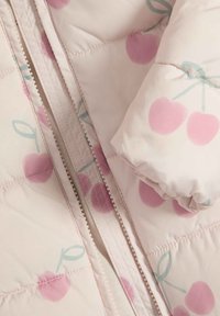 Lys rosa polstret jakke med et kirsebærmønster i pink og grøn, med lynlås lukning og quiltet tekstur. Blødt stoffinish.