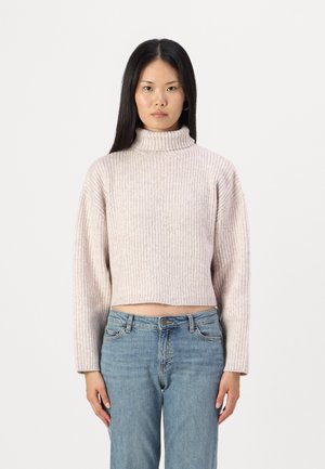 Lys rosa, ribbet høyhalset genser med en cropped design og lange ermer, kombinert med blå høyhalsede jeans.