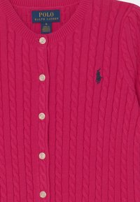 Světlý růžový kardigan z pleteniny s kulatým výstřihem, vybavený pěti knoflíkovými uzávěry a jemným námořnickým logem polo na levé části hrudi.
