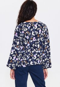 Blusa navy con un motivo floreale astratto colorato. Presenta maniche lunghe e una vestibilità ampia, realizzata in tessuto leggero.