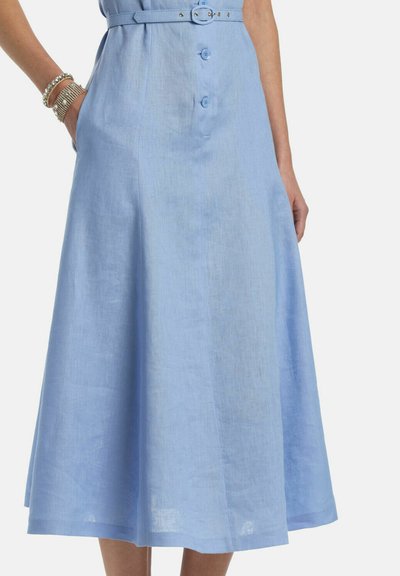 Svetlomodré midi šaty s gombíkmi na prednej strane, so zodpovedajúcim opaskom a vreckami; modelka má na ľavom zápästí strieborné náramky.