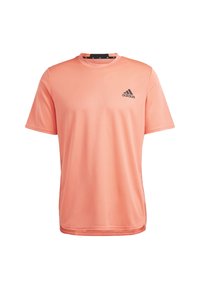 Camiseta atlética de manga corta en suave tela de color coral, diseño de cuello redondo, con un logotipo negro de Adidas en el lado izquierdo del pecho y una textura suave.