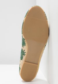 Semelle extérieure d'une chaussure plate beige tissée avec un motif de feuilles de palmier vertes, dotée d'une semelle en caoutchouc texturée et d'une indication de taille 4.