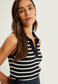 Top polo senza maniche a righe blu navy e bianche con scollo a V e vestibilità aderente, con colletto e giromaniche scuri a contrasto.