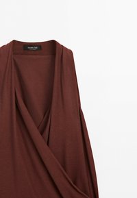 Hnědé šaty bez rukávů s hlubokým výstřihem do V a jemně splývavým látkovým detailem, značka Massimo Dutti.