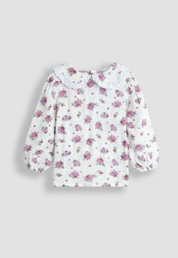 Blusa bianca con motivo floreale in rosa e viola. Presenta un colletto rotondo bordato in pizzo e maniche a sbuffo. Tessuto testurizzato.