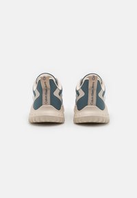 Sneakers Calvin Klein jeans majú modrý a béžový zvršok, textúrovaný materiál a gumovú podrážku s logom na pätnom pásku.