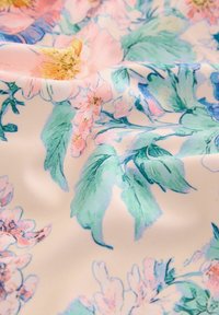 Kwiatowy materiał z różowymi i zielonymi kwiatami w pastelowych odcieniach na kremowym tle, o gładkiej, miękkiej fakturze i subtelnym połysku.