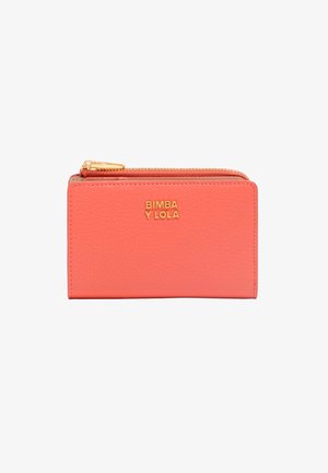 Portefeuille en cuir corail avec une finition texturée, portant un logo doré et une fermeture éclair sur le dessus. Design rectangulaire compact.