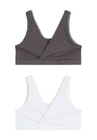 Due bralette in cotone senza maniche, uno grigio scuro e uno bianco, con scollo a V e bordo ondulato lungo i bordi.