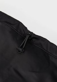 Borsa impermeabile nera con cima arricciata, dotata di chiusura a cordoncino e materiale resistente. Texture liscia, design semplice e dettagli funzionali.