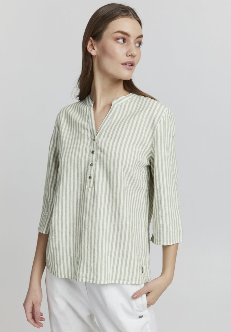 Camisa de manga larga a rayas en verde claro y blanco, con un cuello tipo henley y botones, confeccionada en una tela texturizada.