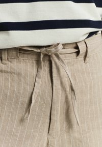 Beige gestreepte linnen broeken met een gestrikt ceintuur, voorzien van een textuurstof en een relaxte pasvorm. De strepen zijn subtiel en verticaal.