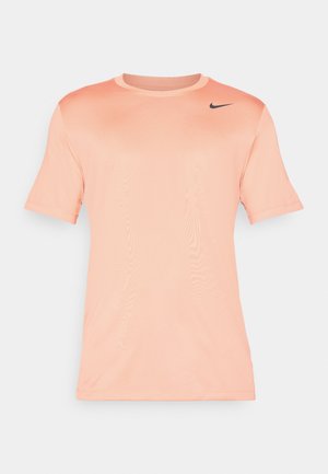 Nike kortærmet t-shirt i lys fersken, lavet af glat stof. Har en rund hals og sort logo på den øverste venstre side.