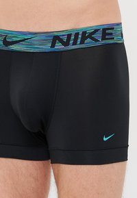 Zwarte atletische boxershorts met een meerkleurige elastische tailleband met de tekst "NIKE". Inclusief een klein turkoois Nike-logo op het been.